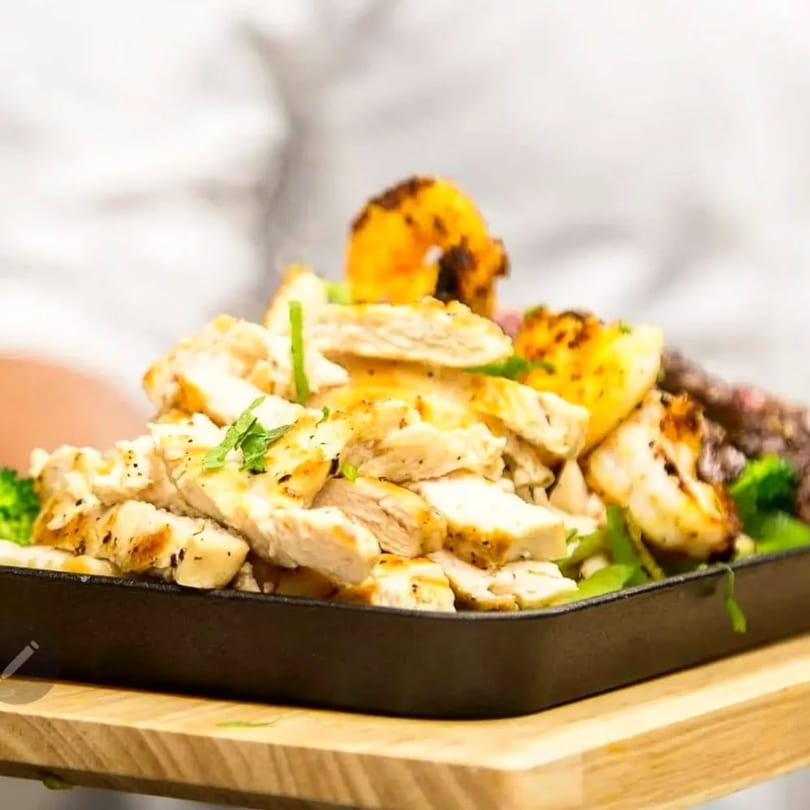 Sizzling fajitas with grilled chicken, shrimp, and vegetables served in a cast iron skillet.